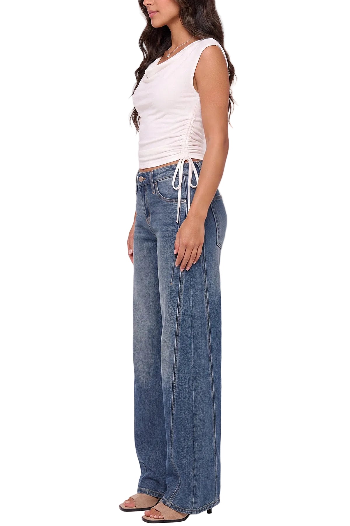 A woman modeling a pair of wide-leg blue jeans with a white drawstring waist, paired with a white sleeveless top and flat sandals, against a plain white background.
