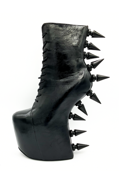 Black platform boot with spikes on a white background
