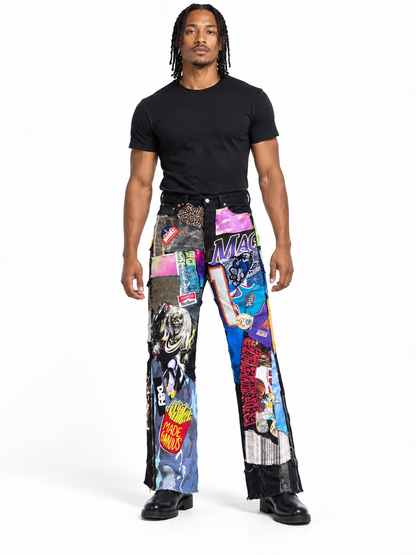 A man modeling a pair of wide-leg pants covered in a colorful collage print of comic book panels, posters, and graphic designs, paired with a black t-shirt and black shoes, on a white studio background.