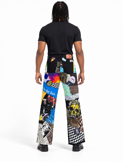 A model shown from the back wearing a black t-shirt and high-waisted, wide-leg patchwork pants with a vibrant collage of graphic prints, animal patterns, and stickers on a white studio background.