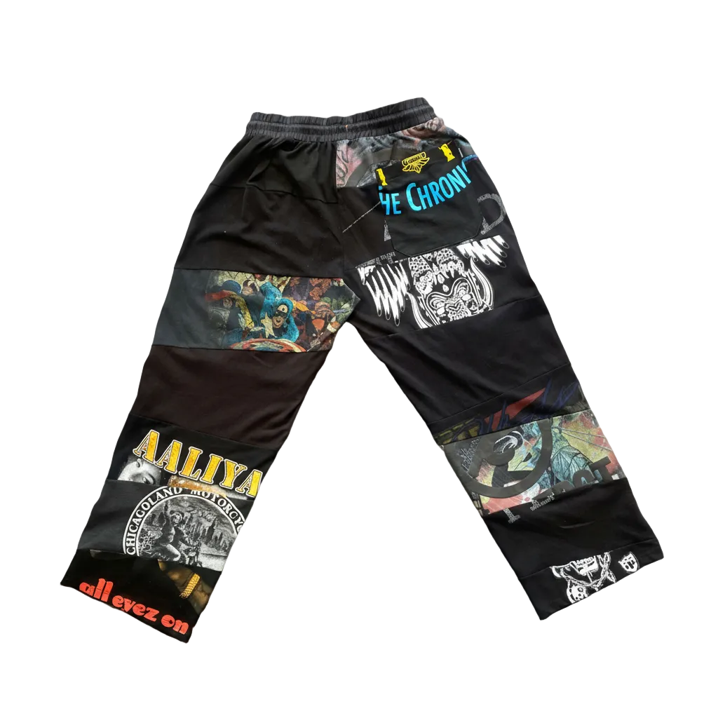 Black patchwork cargo pants with various graphic prints, including 'ALL EYEZ CM' and '7 YE CHRON?' text, laid flat on a light gray background.