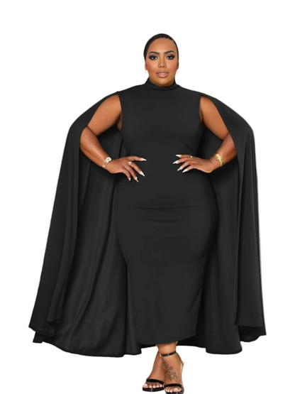 A woman modeling a black sleeveless mock-neck dress with dramatic draped cape-like side panels, standing in a bright white arched interior.
