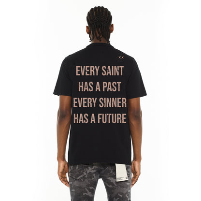 Person wearing a black t-shirt with text on the back, standing against a white background