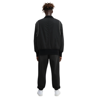 Person wearing a black tracksuit with white piping on a white background