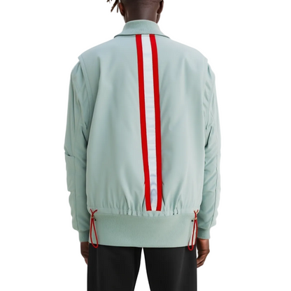 A person shown from the back wearing a mint green bomber-style jacket with a bold red and white vertical stripe down the center back, paired with black pants against a plain white studio background.