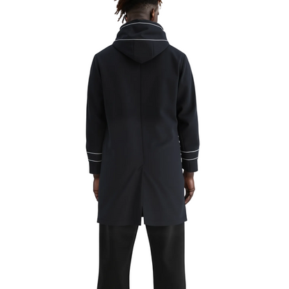 A model shown from the back wearing a black hooded coat with white contrast piping details on the collar and cuffs, paired with black trousers, against a plain white studio background.