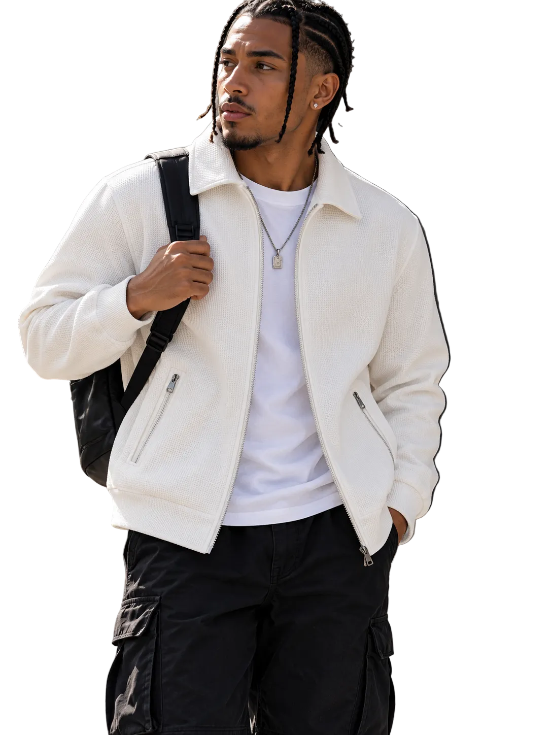 A man wearing a white zip-up fleece jacket over a white t-shirt and black cargo pants, carrying a black backpack, standing outdoors against a stone wall.