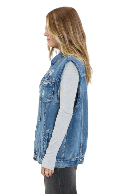 Woman wearing a denim vest over a gray long-sleeve shirt on a white background