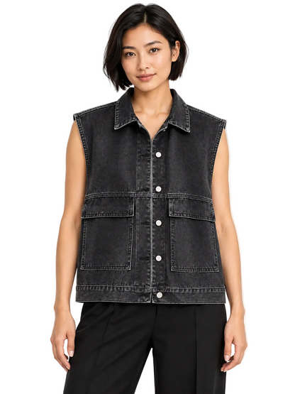 A woman wearing a sleeveless black denim vest with a button-down front and two large front flap pockets, paired with black pants, against a plain white background.