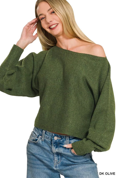 Woman wearing a green off-shoulder sweater and blue jeans on a white background