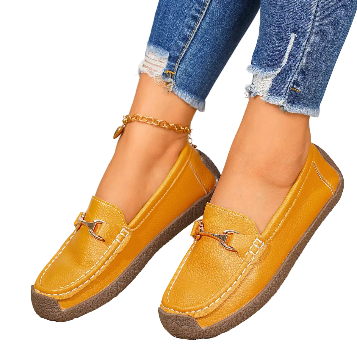 A pair of mustard yellow leather slip-on loafers with brown soles and gold-tone hardware, shown on a model's feet wearing blue distressed jeans.