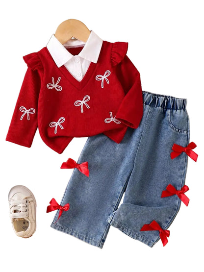 A toddler girl's two-piece outfit set featuring a red knit sweater vest with white embroidered bow details and a white collar, paired with light blue denim shorts decorated with red ribbon bows. The set is styled in a flat-lay arrangement on a wooden surface with decorative props.
