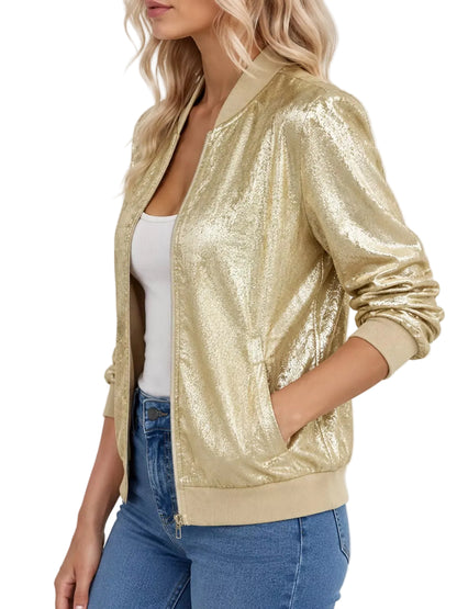 A woman wearing a shiny metallic gold bomber jacket over a white tank top and blue jeans, shown from the side against a light gray studio background.