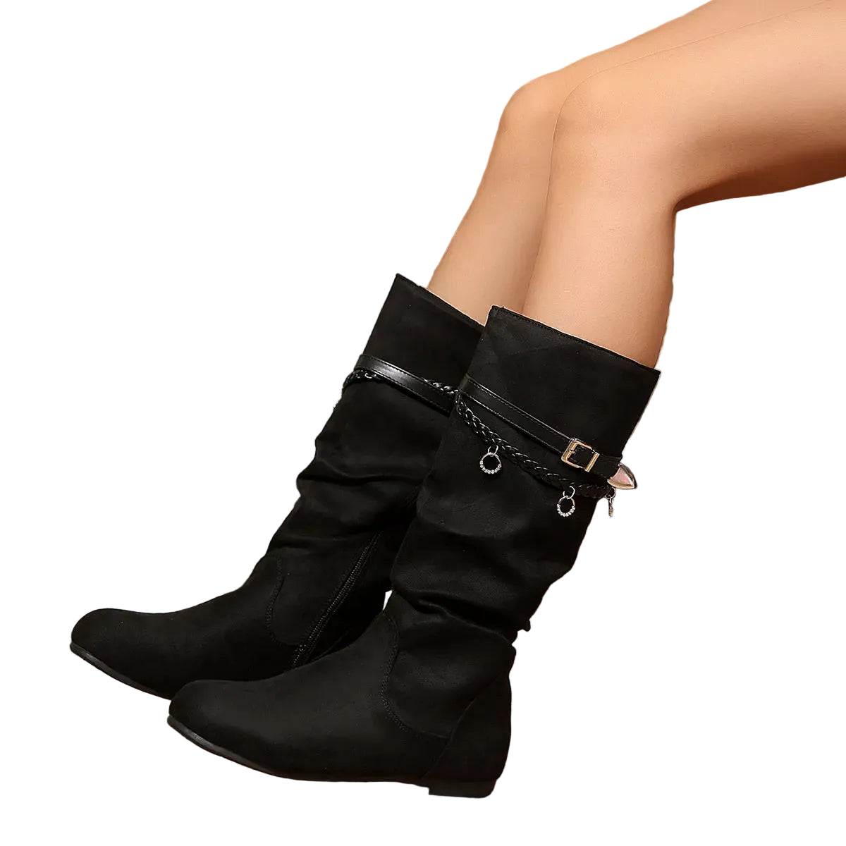 A pair of black mid-calf boots with decorative chain and buckle details, shown on a model's feet against a rustic wooden background.