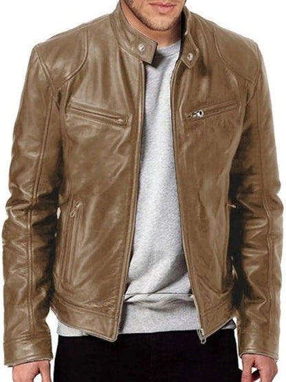 A man wearing a brown leather jacket over a light gray t-shirt and black pants, shown from the chin down against a plain white background.