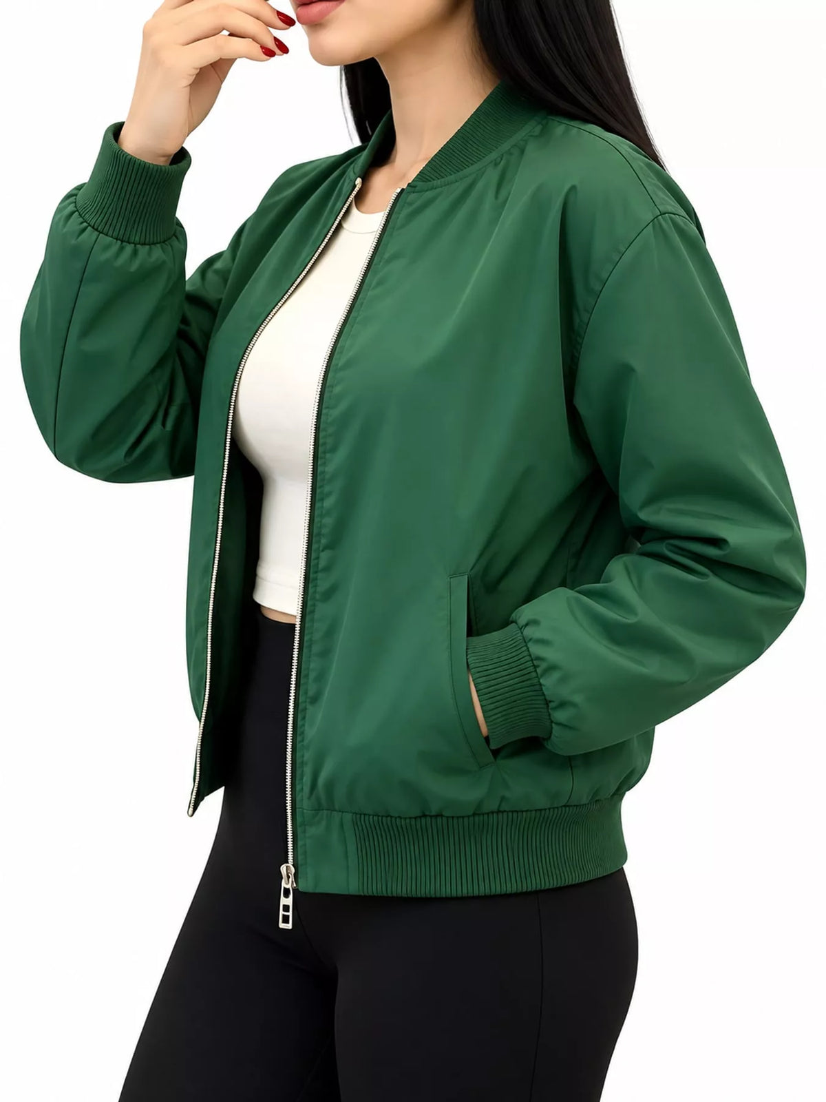 A woman wearing a dark green bomber jacket over a white crop top and black pants, shown from the chin down against a plain white background.