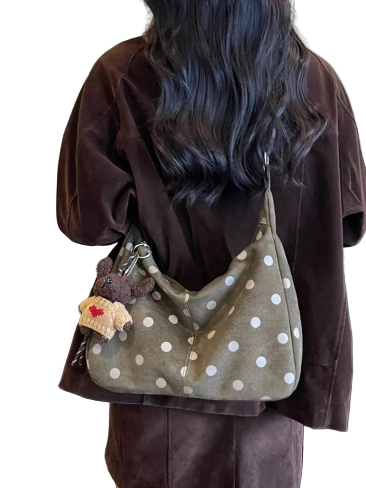A person wearing a brown velvet jacket and brown pants, shown from behind, carrying a brown suede slouchy shoulder bag with white polka dots. The bag has a small plush keychain attached.