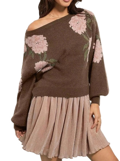 A woman wearing a brown off-the-shoulder knit sweater with large pink floral patterns and a pleated light pink skirt, shown against a plain light background.