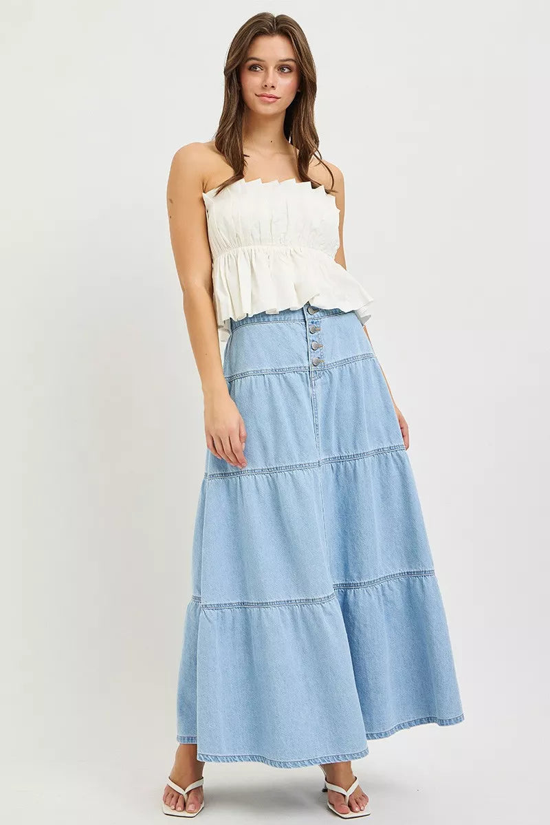 Woman wearing a white top and light blue denim skirt on a plain background
