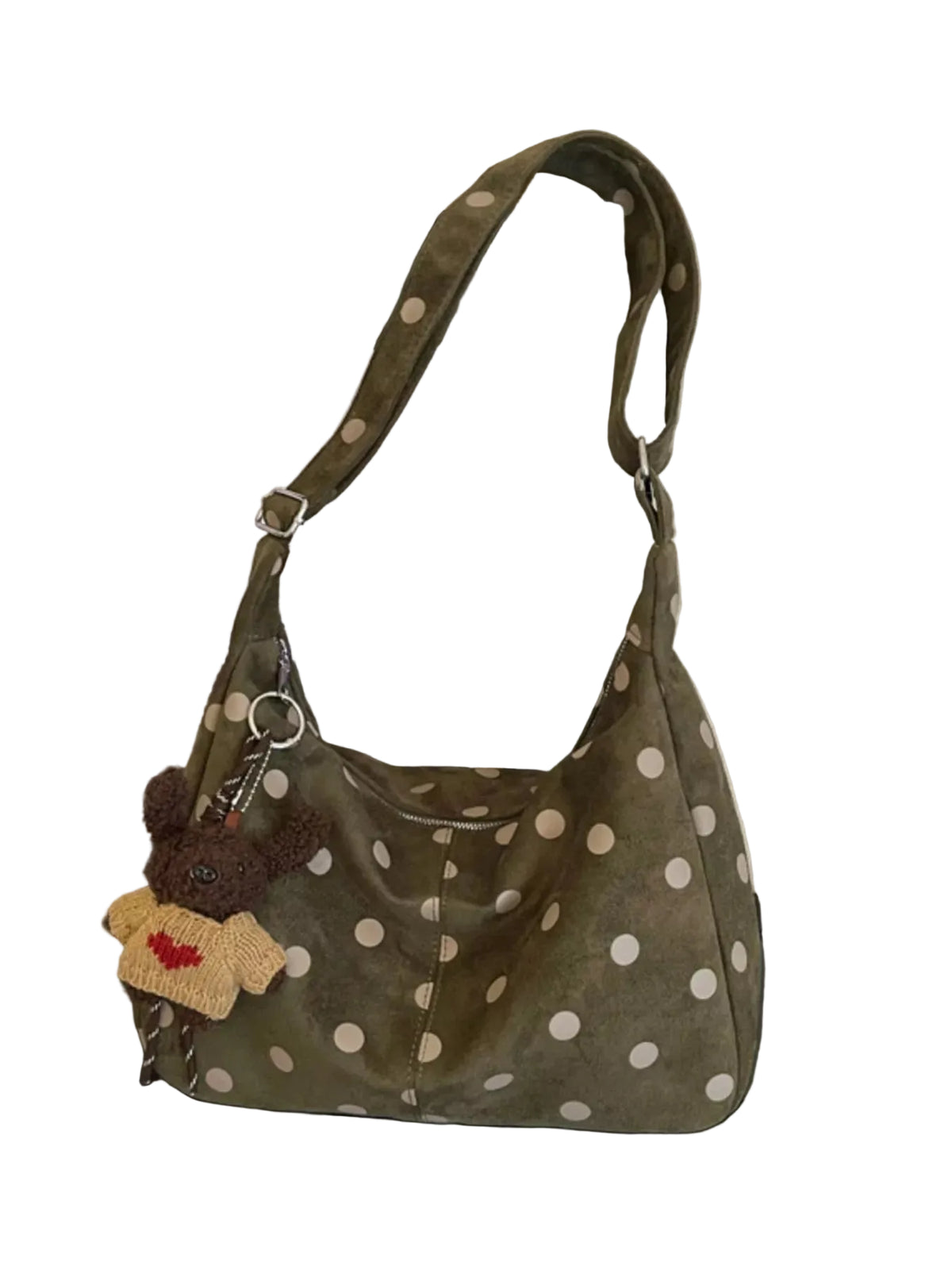 An olive green shoulder bag with white polka dots, featuring a brown plush toy keychain with a red heart, resting on a black surface in front of a framed picture.