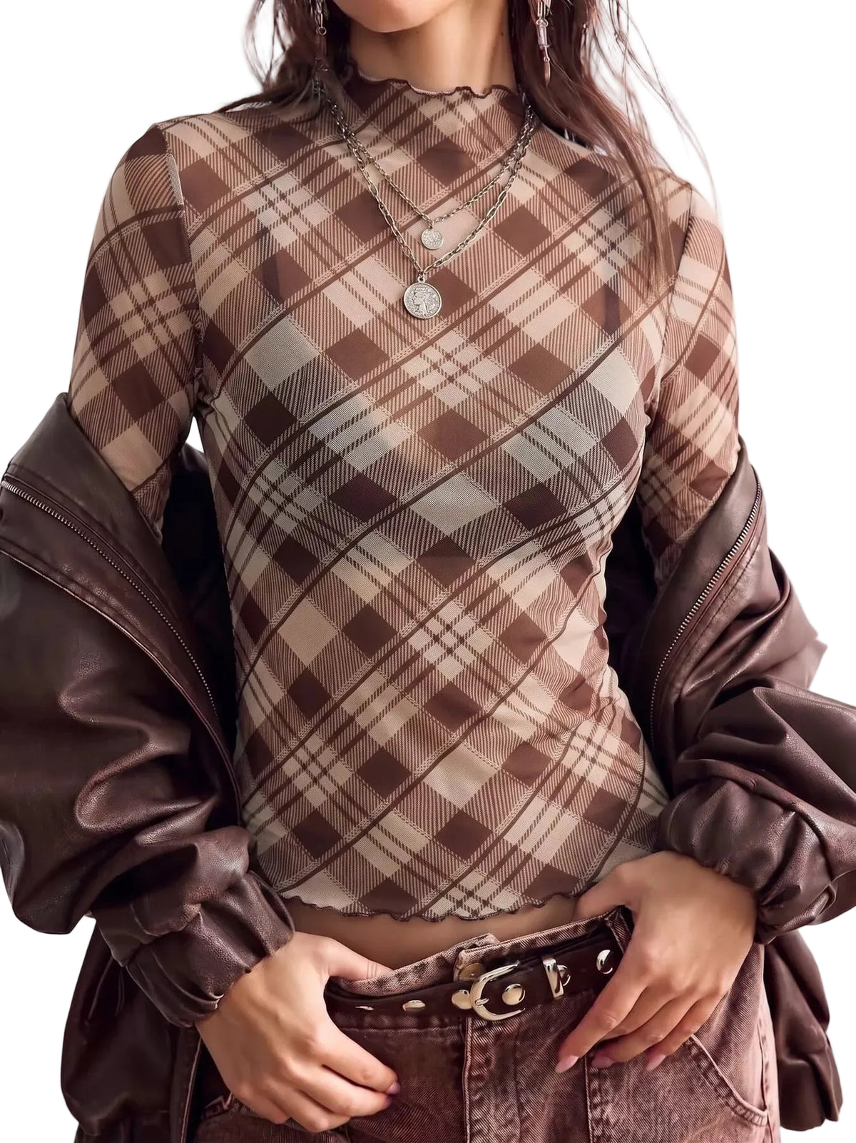 A woman wearing a brown and beige plaid mock neck top with sheer long sleeves, layered under a dark brown faux-leather jacket, paired with brown jeans.