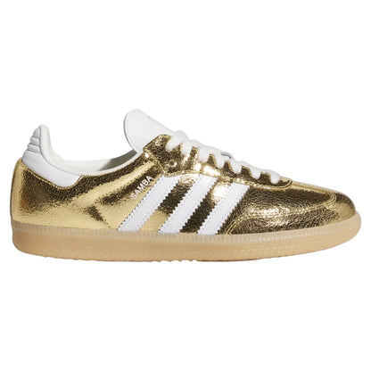 A metallic gold Adidas Gazelle sneaker with white leather stripes, white laces, and a beige gum sole, shown in a side profile on a white background.