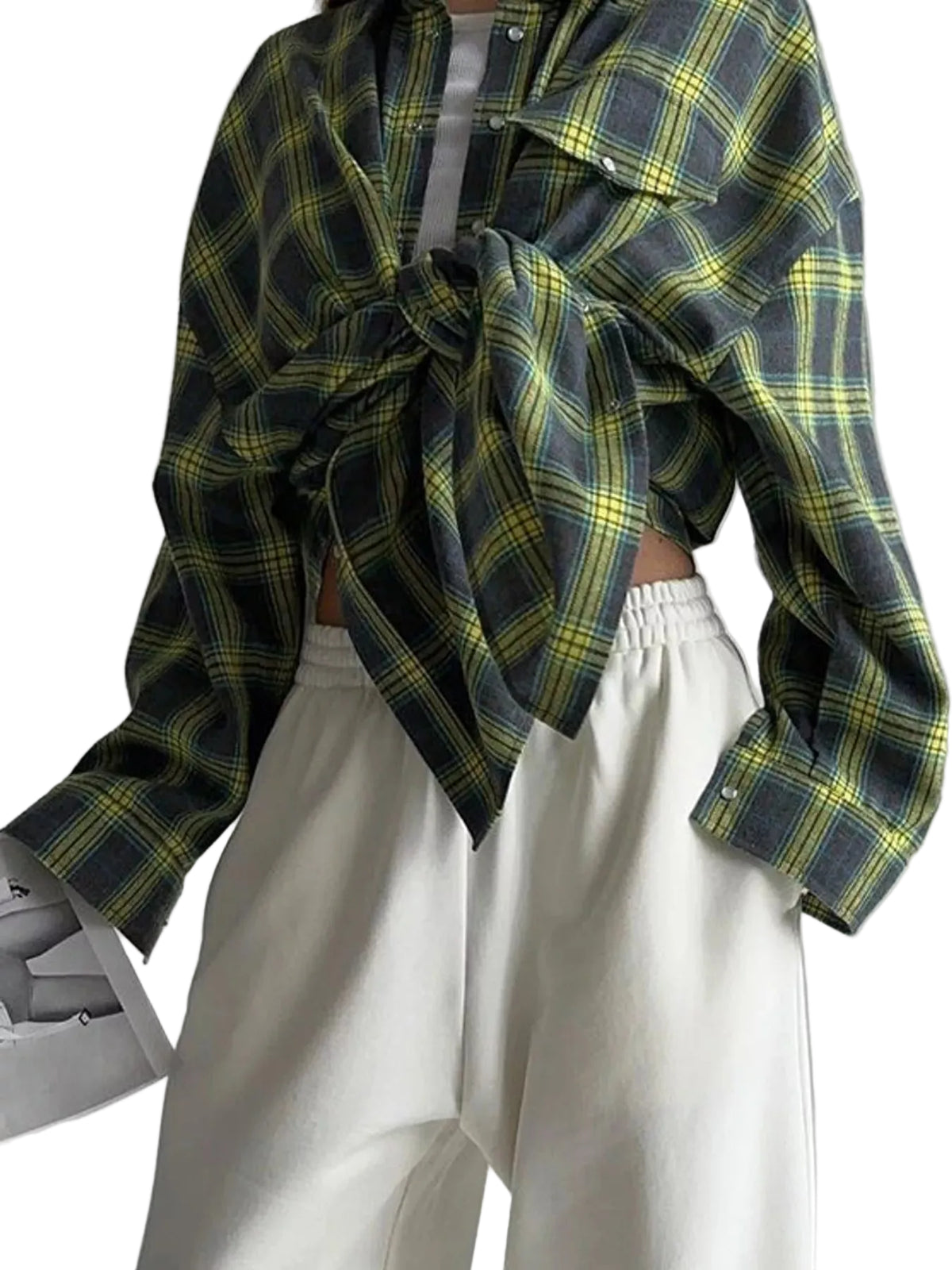 A person wearing a dark green and yellow plaid button-up shirt tied at the waist over a white top, paired with white wide-leg pants, against a plain light gray background.