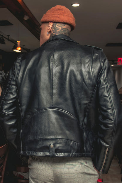 Person wearing a black leather jacket and orange beanie in an indoor setting