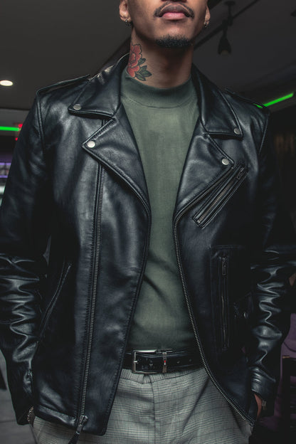 Person wearing a black leather jacket and green shirt in an indoor setting