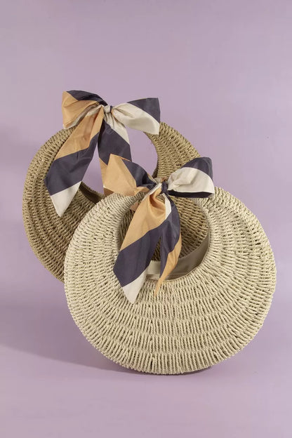 Woven straw hat with a striped scarf on a light purple background