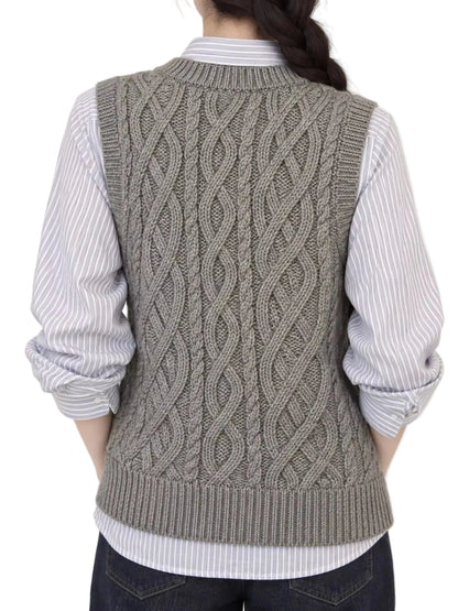 A person shown from the back wearing a gray cable-knit sweater vest over a white and gray striped button-up shirt, paired with dark jeans, against a plain light background.