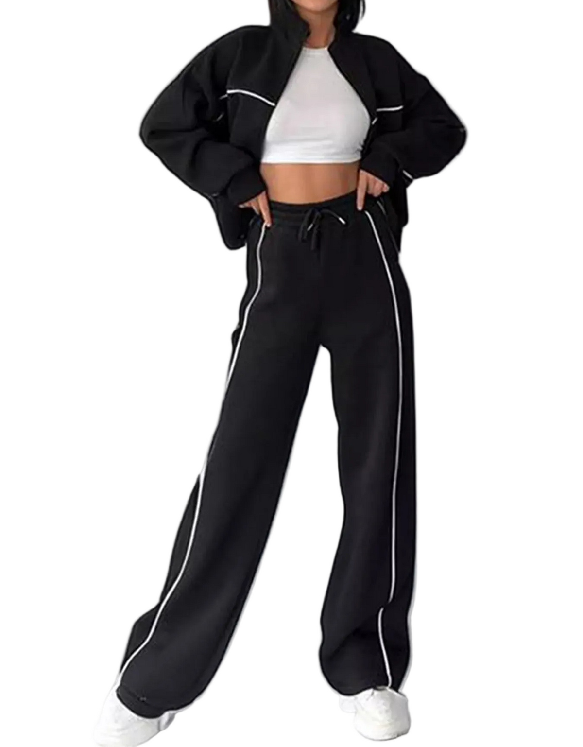 A model wearing black wide-leg sweatpants with white piping details, styled with a black cropped jacket, white crop top, and white sneakers against a plain white background.