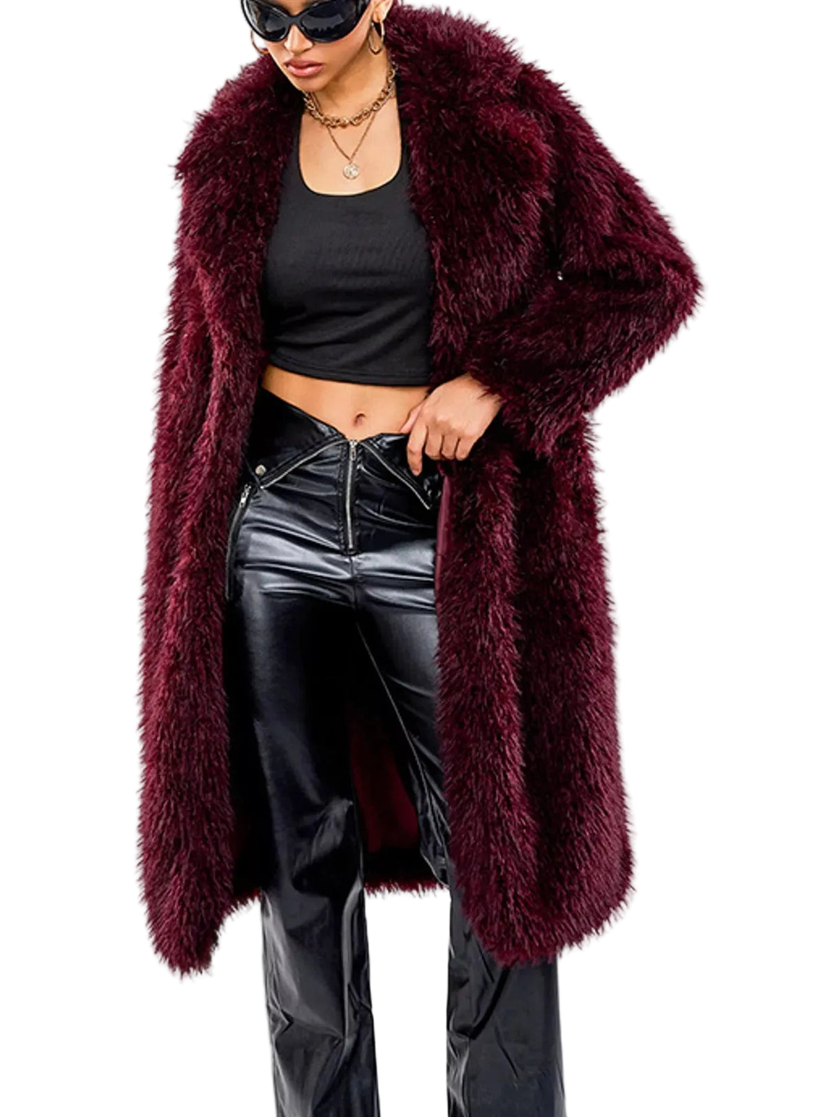 A woman wearing a long, plush faux fur coat in deep burgundy, styled with a black crop top, black faux-leather pants, and black sunglasses against a plain white background.