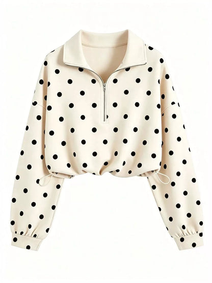 A cream-colored long-sleeve quarter-zip pullover sweatshirt with a black polka dot pattern, featuring a mock neck collar and elasticized cuffs.