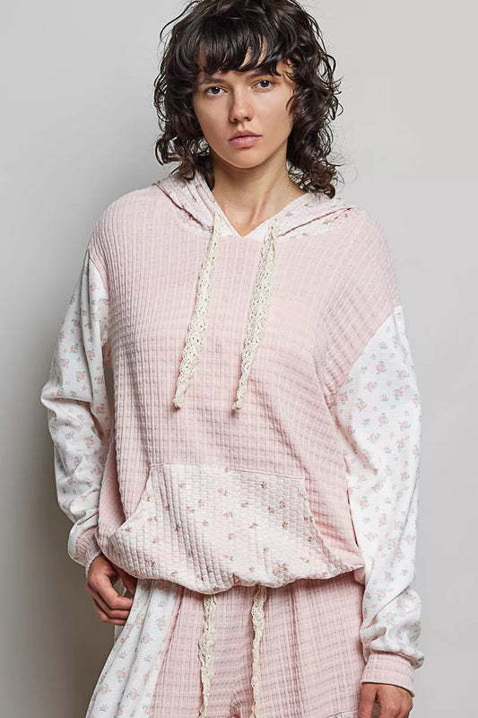 Person wearing a pink textured hoodie and pants on a plain background