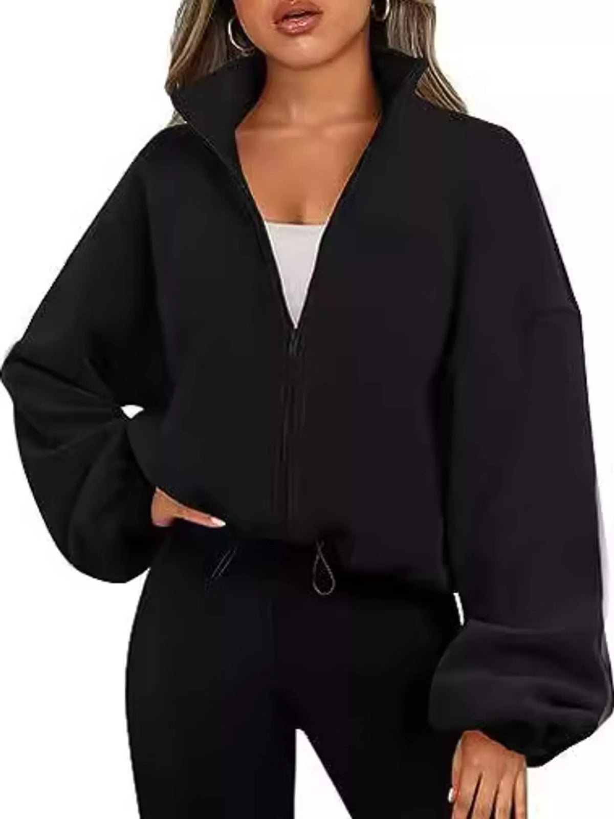 A woman wearing a black cropped zip-up jacket with oversized balloon sleeves and black jogger pants, shown against a plain white background.
