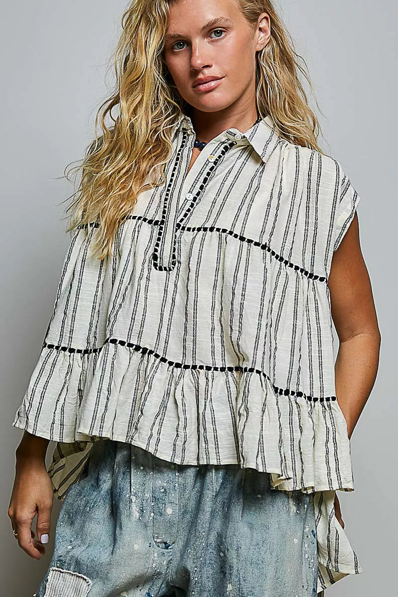 Woman wearing a striped shirt with ruffled layers against a gray background