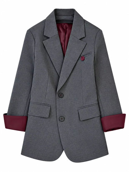 A gray double-breasted blazer with a dark burgundy lining visible at the collar, cuffs, and pocket, featuring a matching burgundy button on the chest pocket.