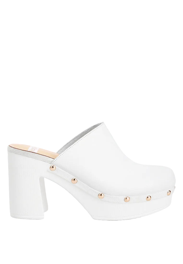 White clog shoe with gold studs on a light gray background