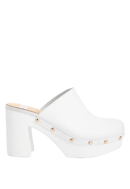 White clog shoe with gold studs on a light gray background