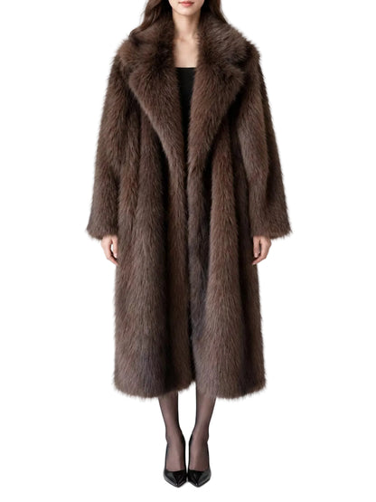 A model wearing a long, luxurious brown fur coat with a wide collar, styled over a black top and black tights with black pointed-toe heels, set against a plain white studio background.