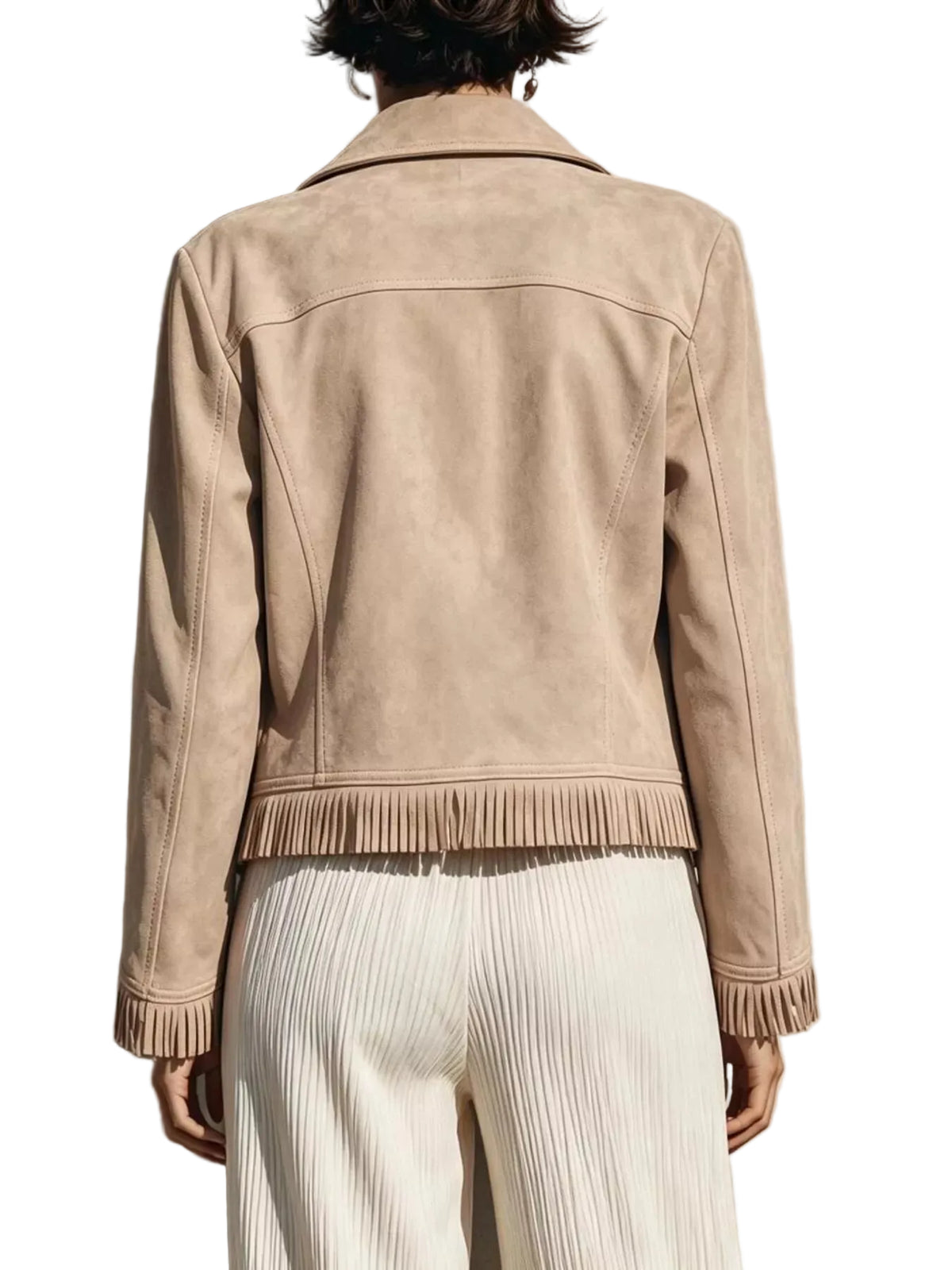 A person shown from the back wearing a light beige suede jacket with fringe trim at the hem and cuffs, paired with white pleated trousers, standing against a textured wall with a strong shadow.