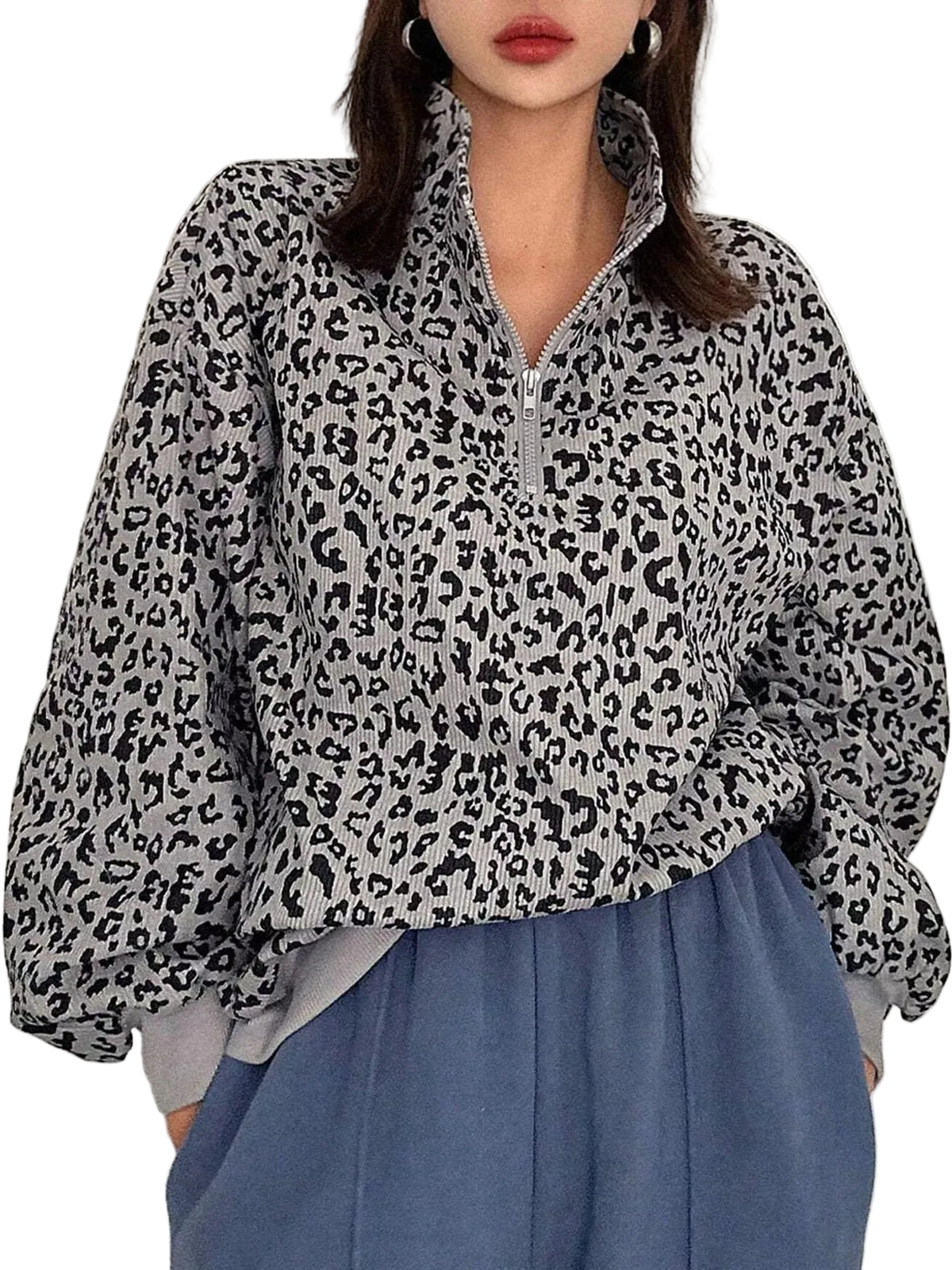 A woman wearing a gray and black leopard print half-zip pullover top with voluminous balloon sleeves, paired with blue wide-leg pants.