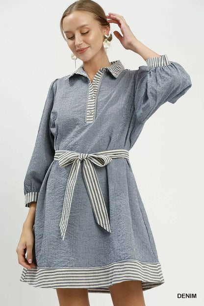 Woman wearing a denim dress with striped details on a white background