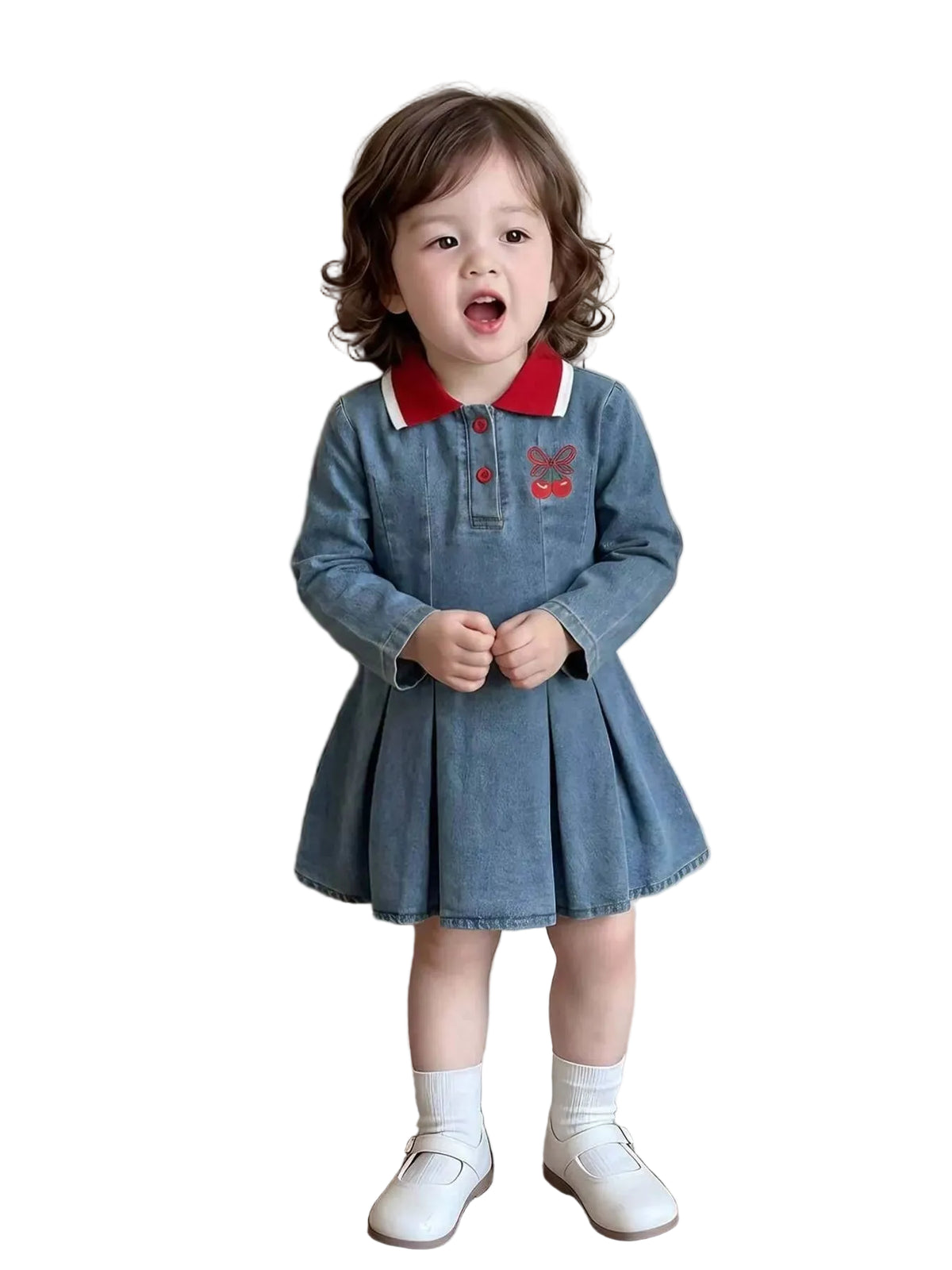 A toddler girl wearing a blue denim long-sleeve dress with a red and white collar, standing in front of a textured beige wall.