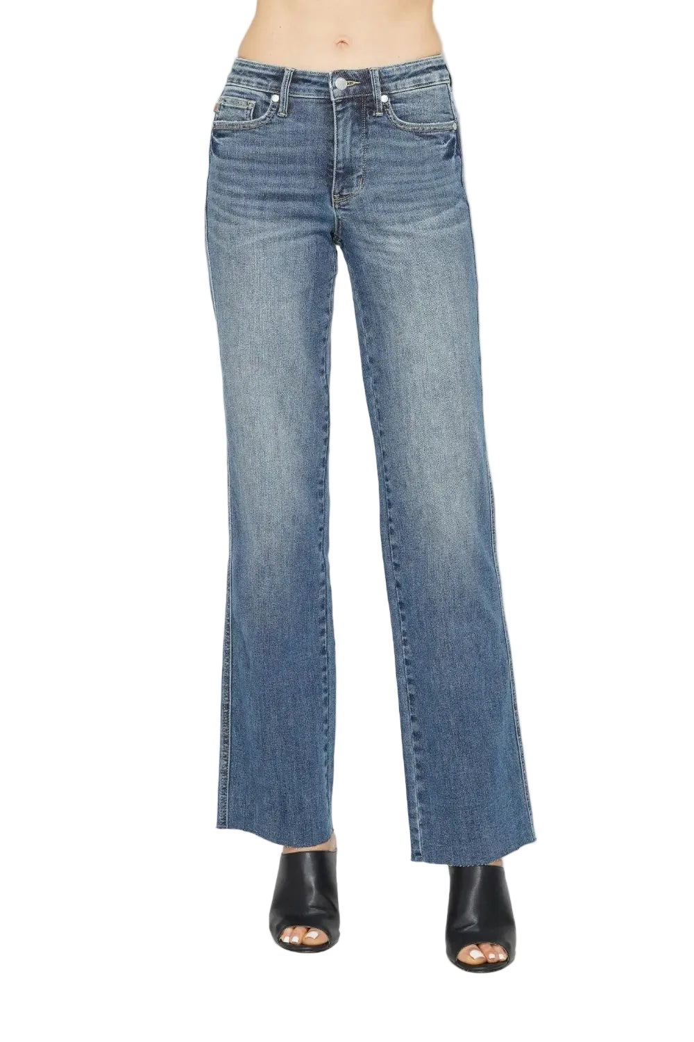 A model from the waist down wearing medium-wash blue denim jeans with a straight-to-flare leg and black open-toe heeled sandals, photographed against a plain white studio background.