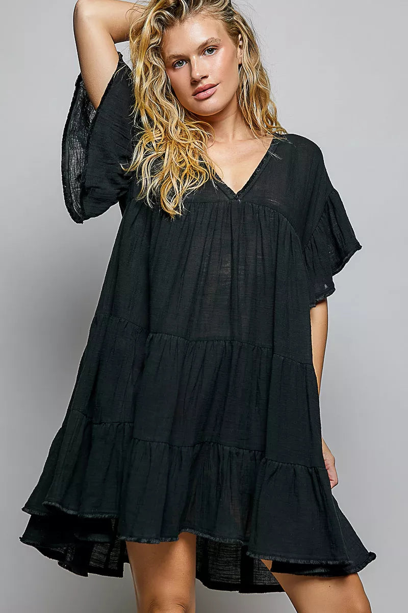 Woman wearing a black tiered dress against a gray background