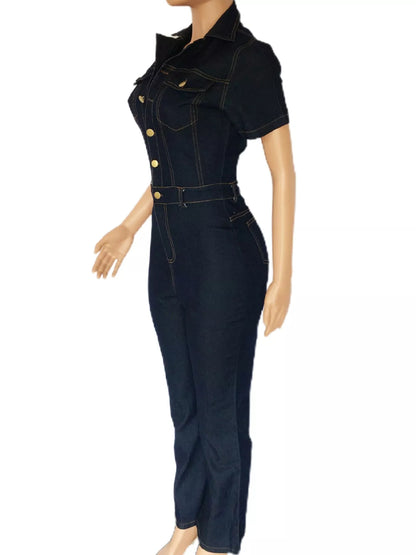 A dark wash denim jumpsuit with short sleeves, a pointed collar, gold-tone buttons down the front, and a matching belt, displayed on a mannequin against a white background.