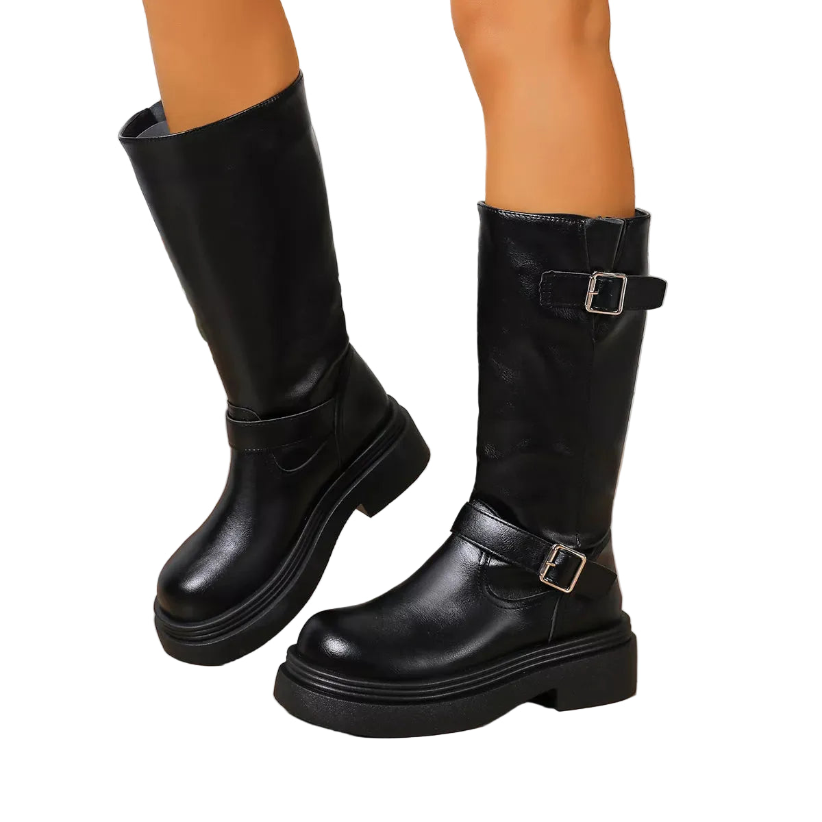 A pair of black knee-high leather boots with buckle straps, shown on a model's legs against a light wood floor and white paneled wall.