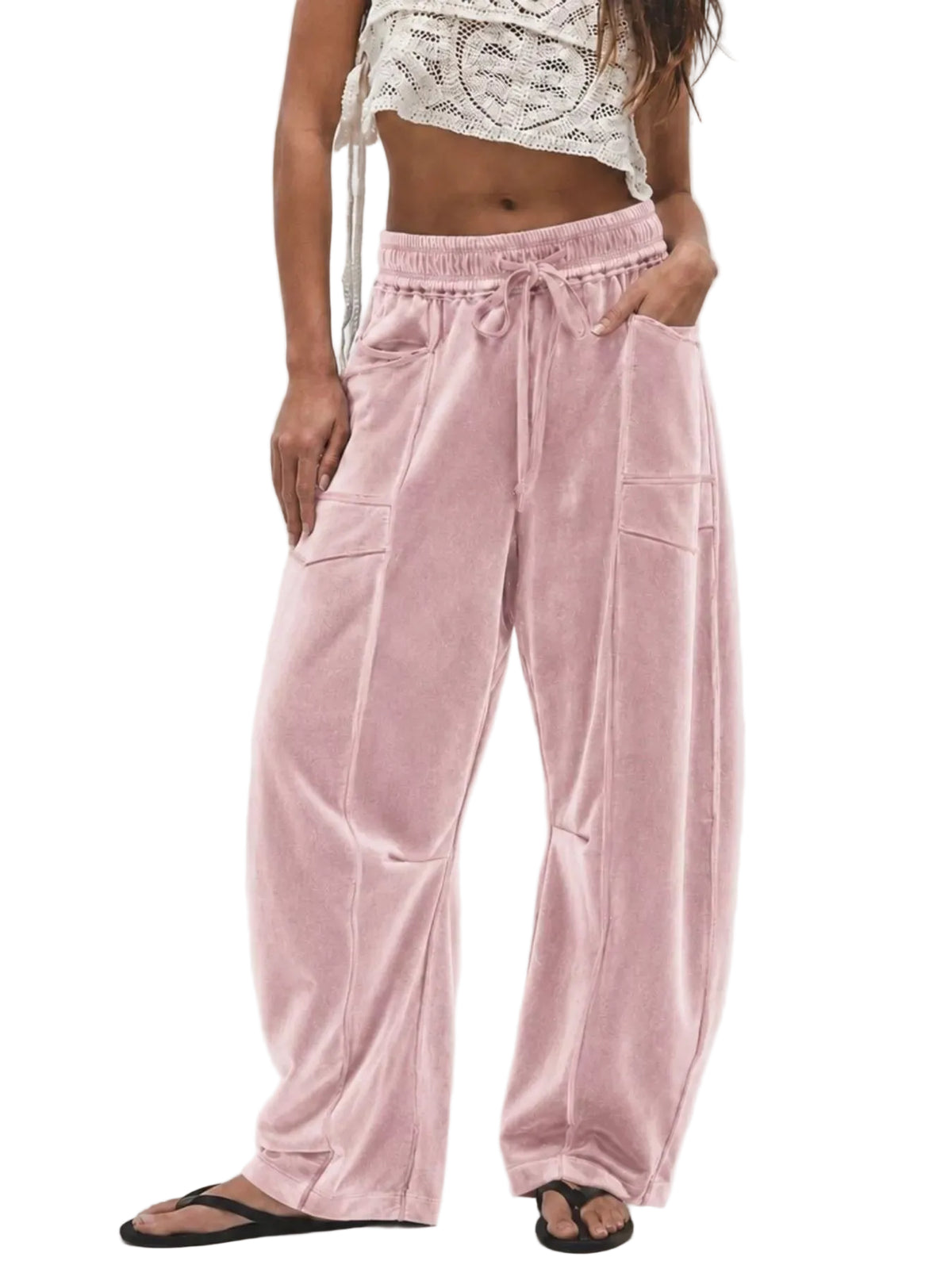 A model wearing dusty pink velvet wide-leg pants with a drawstring waist, side pockets, and front patch pockets, paired with a white crochet crop top and black flip-flops against a light gray background.
